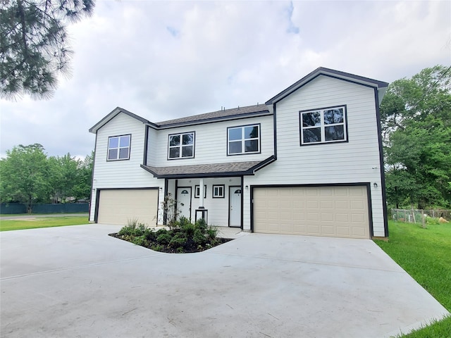 view of front of home with a shingled roof, an attached garage, driveway, and a front lawn