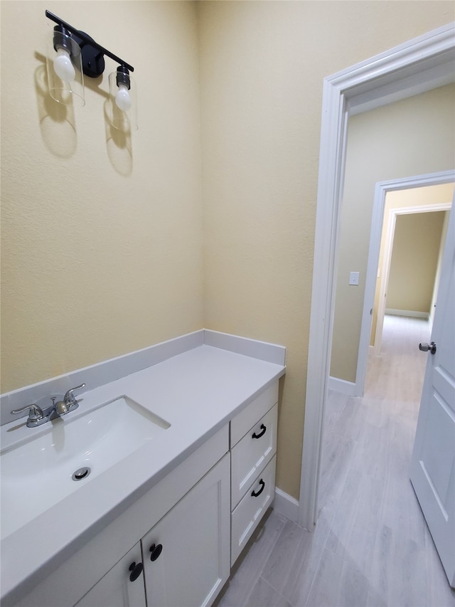 bathroom featuring vanity, baseboards, and wood finished floors