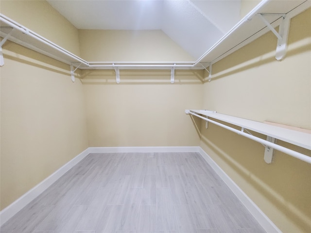 walk in closet with wood finished floors and vaulted ceiling