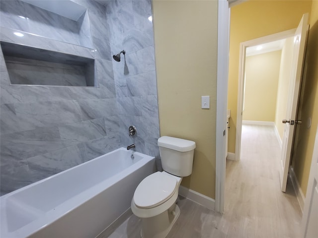 bathroom featuring toilet, baseboards, tub / shower combination, and wood finished floors