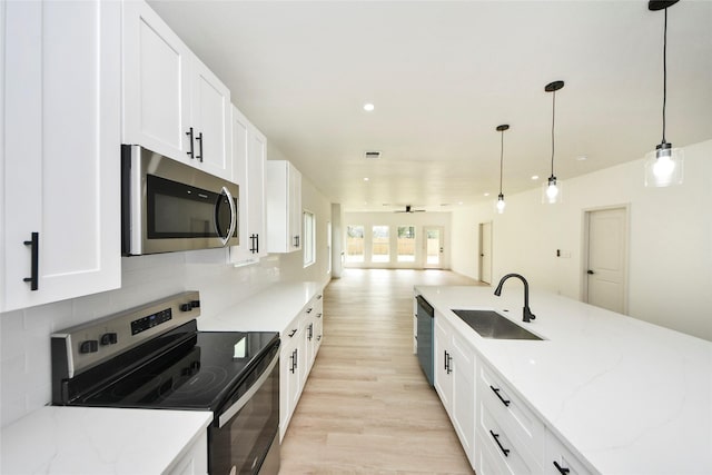 600 Rd 5105, Cleveland, TX 77327 - kitchen featuring light wood-type flooring, a sink, open floor plan, stainless steel appliances, and white cabinetry