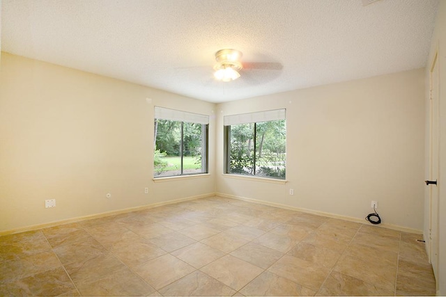 unfurnished room with a ceiling fan, a textured ceiling, and baseboards