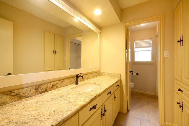 bathroom with vanity, baseboards, tile patterned flooring, and toilet