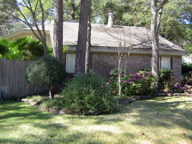 view of property exterior with a lawn, brick siding, fence, and a shingled roof