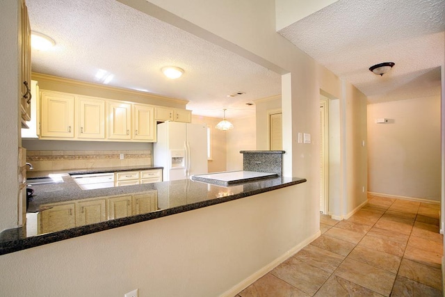 kitchen featuring a sink, white refrigerator with ice dispenser, a textured ceiling, a peninsula, and baseboards