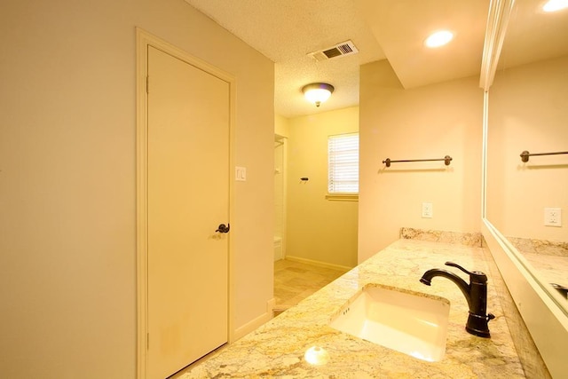 full bathroom with visible vents, a sink, a textured ceiling, and double vanity