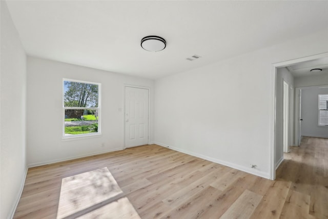 empty room with baseboards, light wood finished floors, and visible vents