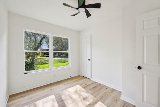 empty room featuring baseboards, ceiling fan, light wood finished floors, and a wealth of natural light