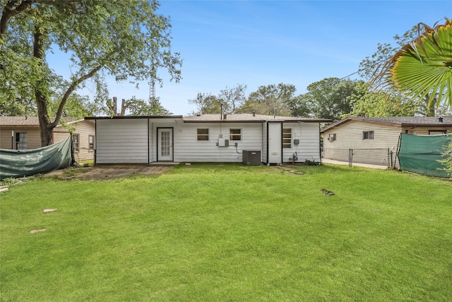 rear view of property with a lawn, fence, and cooling unit