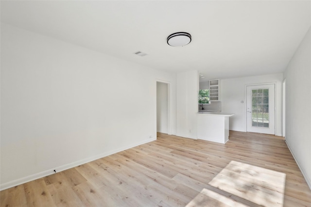 unfurnished living room featuring baseboards, visible vents, and light wood-type flooring