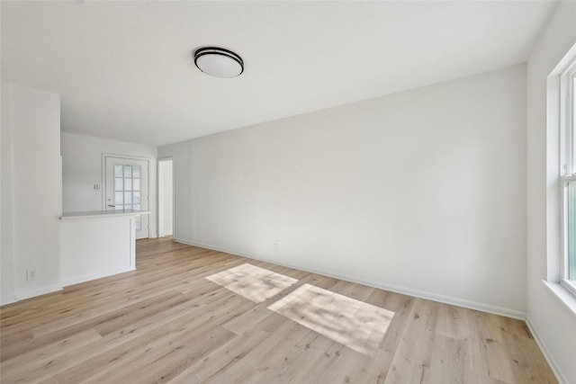 unfurnished room featuring baseboards and light wood-type flooring