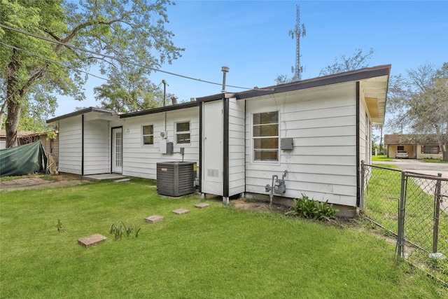 back of property featuring a lawn, central AC, and fence