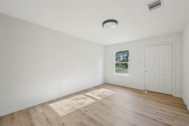 unfurnished room featuring baseboards, light wood-style flooring, and visible vents