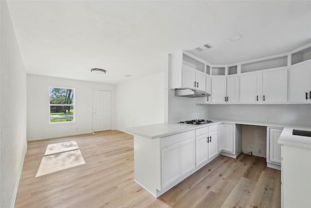 kitchen with visible vents, light countertops, white cabinetry, under cabinet range hood, and light wood-style flooring