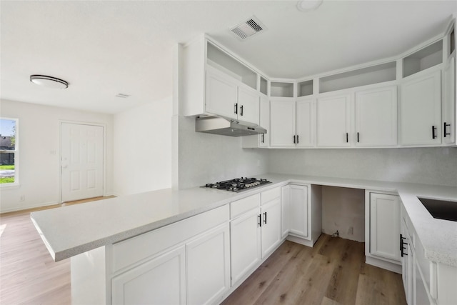 kitchen with light wood-style floors, white cabinetry, stainless steel gas stovetop, under cabinet range hood, and visible vents