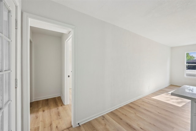 spare room featuring baseboards and light wood-style floors