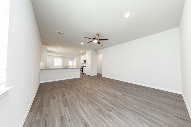 unfurnished living room featuring ceiling fan, recessed lighting, baseboards, wood finished floors, and visible vents