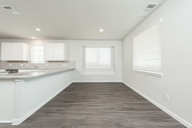 kitchen with visible vents, a sink, white cabinetry, and backsplash