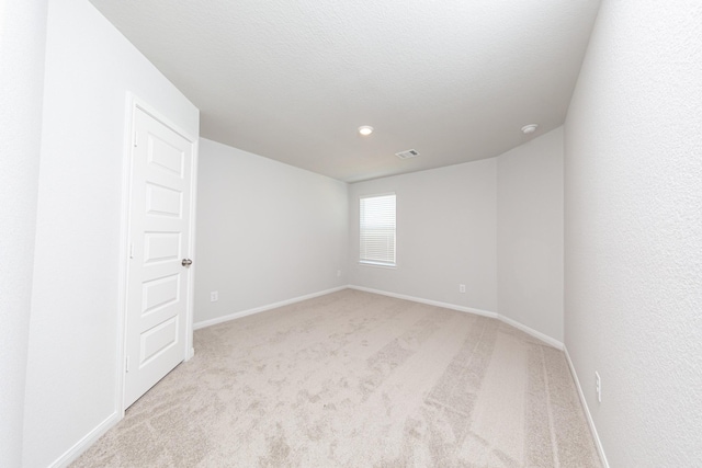 unfurnished room with baseboards, light colored carpet, and visible vents