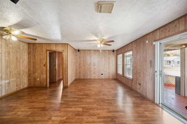 8152 Lenore St, Houston, TX 77017 - spare room featuring wooden walls, ceiling fan, visible vents, and wood finished floors