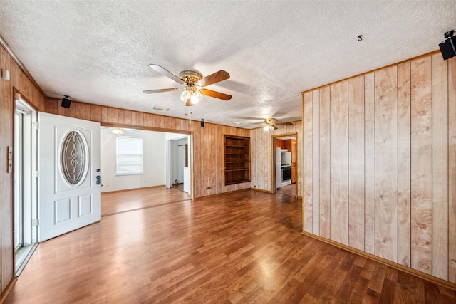 8152 Lenore St, Houston, TX 77017 - unfurnished living room featuring visible vents, wood finished floors, wooden walls, a textured ceiling, and a ceiling fan