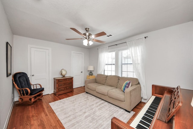 living room featuring baseboards, a ceiling fan, wood finished floors, and visible vents