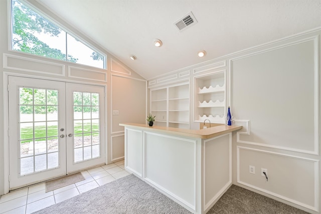 bar with light tile patterned floors, visible vents, french doors, and a decorative wall