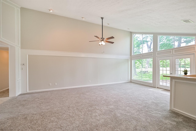 unfurnished living room with visible vents, a ceiling fan, carpet, and high vaulted ceiling