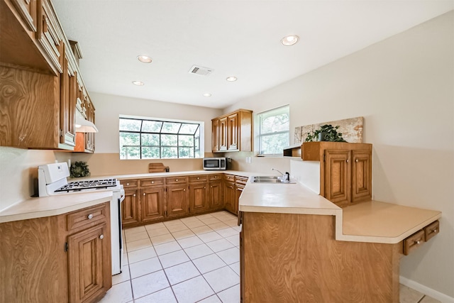 kitchen featuring visible vents, stainless steel microwave, white range with gas stovetop, and light tile patterned floors