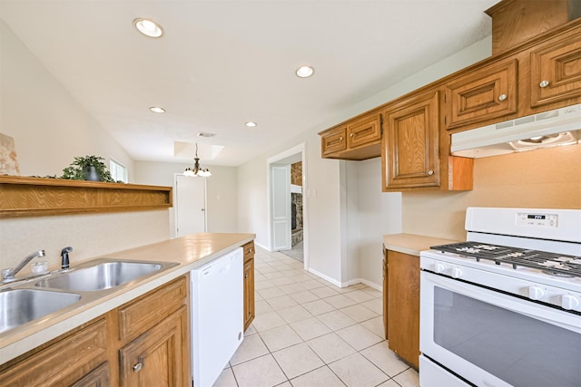 kitchen featuring white appliances, light countertops, under cabinet range hood, brown cabinets, and a sink