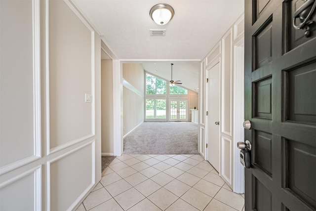 hall with light tile patterned flooring, light colored carpet, lofted ceiling, and visible vents