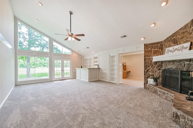 unfurnished living room with visible vents, built in features, light carpet, high vaulted ceiling, and french doors