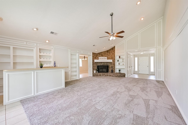 unfurnished living room with a stone fireplace, a ceiling fan, built in features, and visible vents