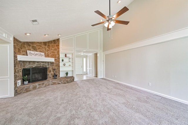 unfurnished living room featuring ceiling fan, a fireplace, built in shelves, high vaulted ceiling, and carpet floors
