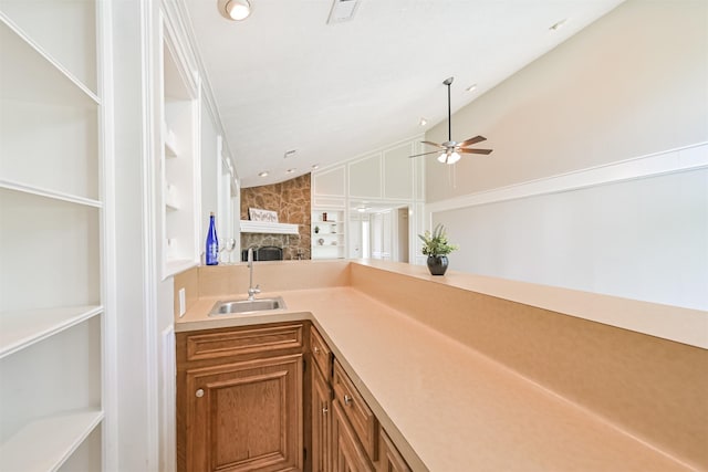 kitchen with a ceiling fan, visible vents, a fireplace, brown cabinets, and a sink