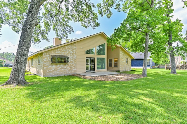 rear view of property featuring a lawn, brick siding, a chimney, and a patio