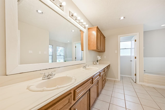 bathroom featuring tile patterned flooring, a sink, baseboards, and double vanity