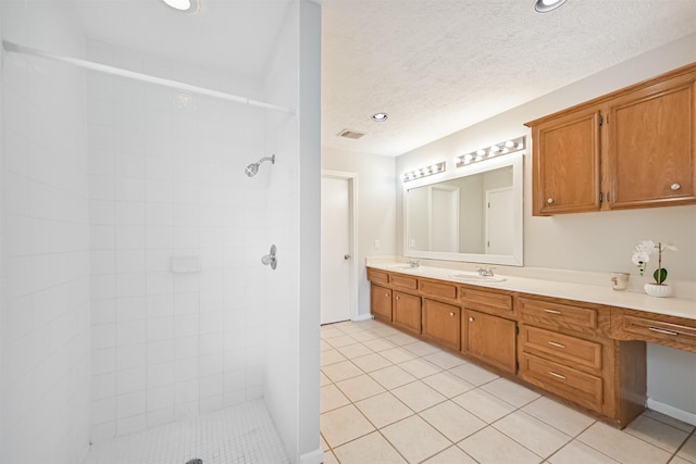 bathroom with a sink, tile patterned floors, double vanity, and tiled shower