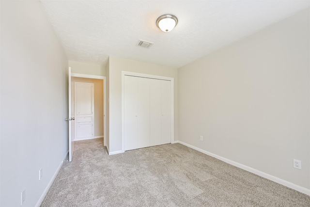 unfurnished bedroom featuring baseboards, carpet, a closet, and visible vents