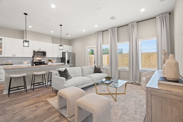 living room featuring recessed lighting, visible vents, and light wood-style flooring