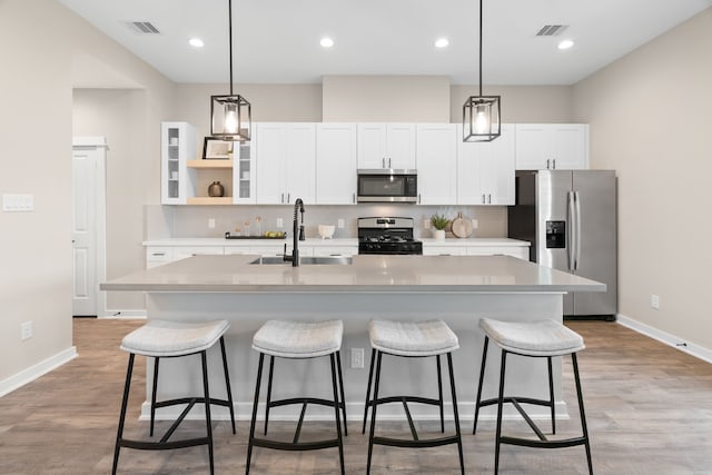 kitchen with visible vents, white cabinetry, appliances with stainless steel finishes, and an island with sink