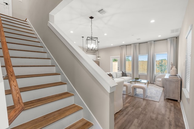 stairs with recessed lighting, a chandelier, wood finished floors, and visible vents