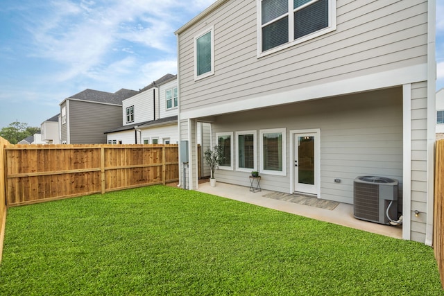 back of property with a yard, central AC, a fenced backyard, and a patio area