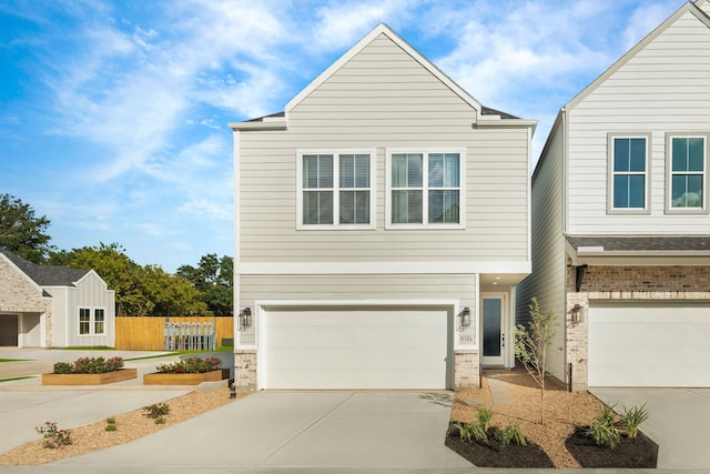 view of front facade with an attached garage, fence, driveway, and brick siding