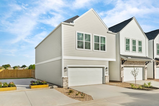 view of front of property featuring an attached garage, fence, and driveway