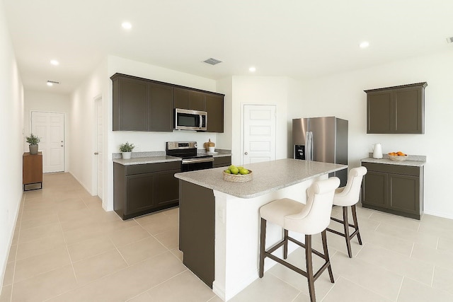kitchen with a breakfast bar area, light countertops, a center island, stainless steel appliances, and visible vents