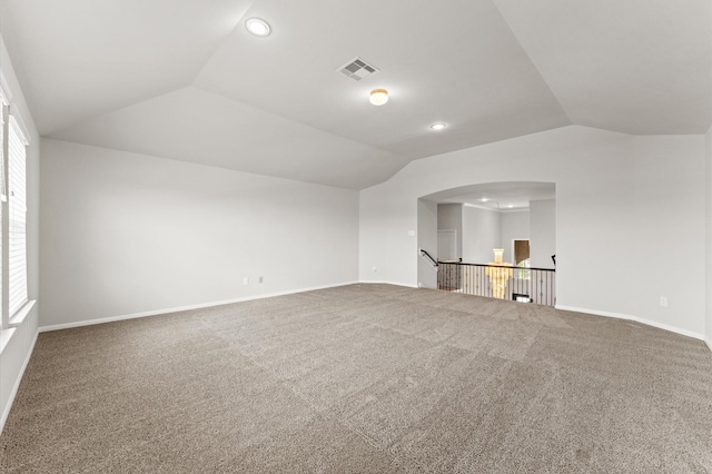 unfurnished living room with carpet floors, baseboards, vaulted ceiling, and visible vents