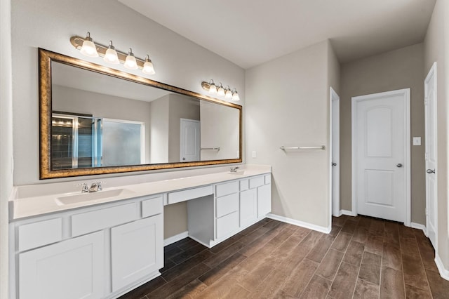 bathroom with double vanity, baseboards, a sink, and wood finished floors