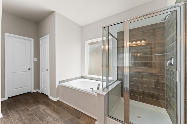 full bathroom with baseboards, a stall shower, and a garden tub