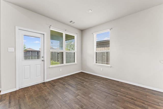 empty room featuring baseboards, visible vents, and wood finished floors
